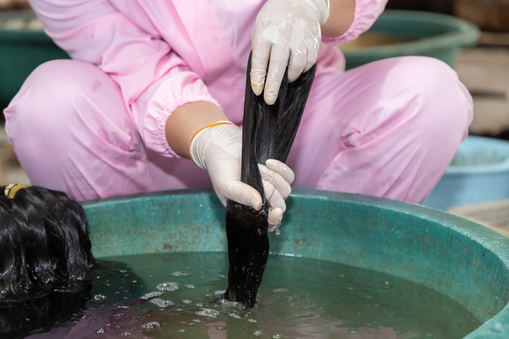 The worker is washing human hair.